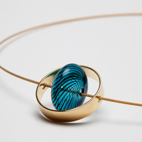 Collar artesanal Xar de plata 925 chapada en oro de 18k con forma ovalada de vidrio azul y cable de acero galvanizado dorado diseñado por Belen Bajo